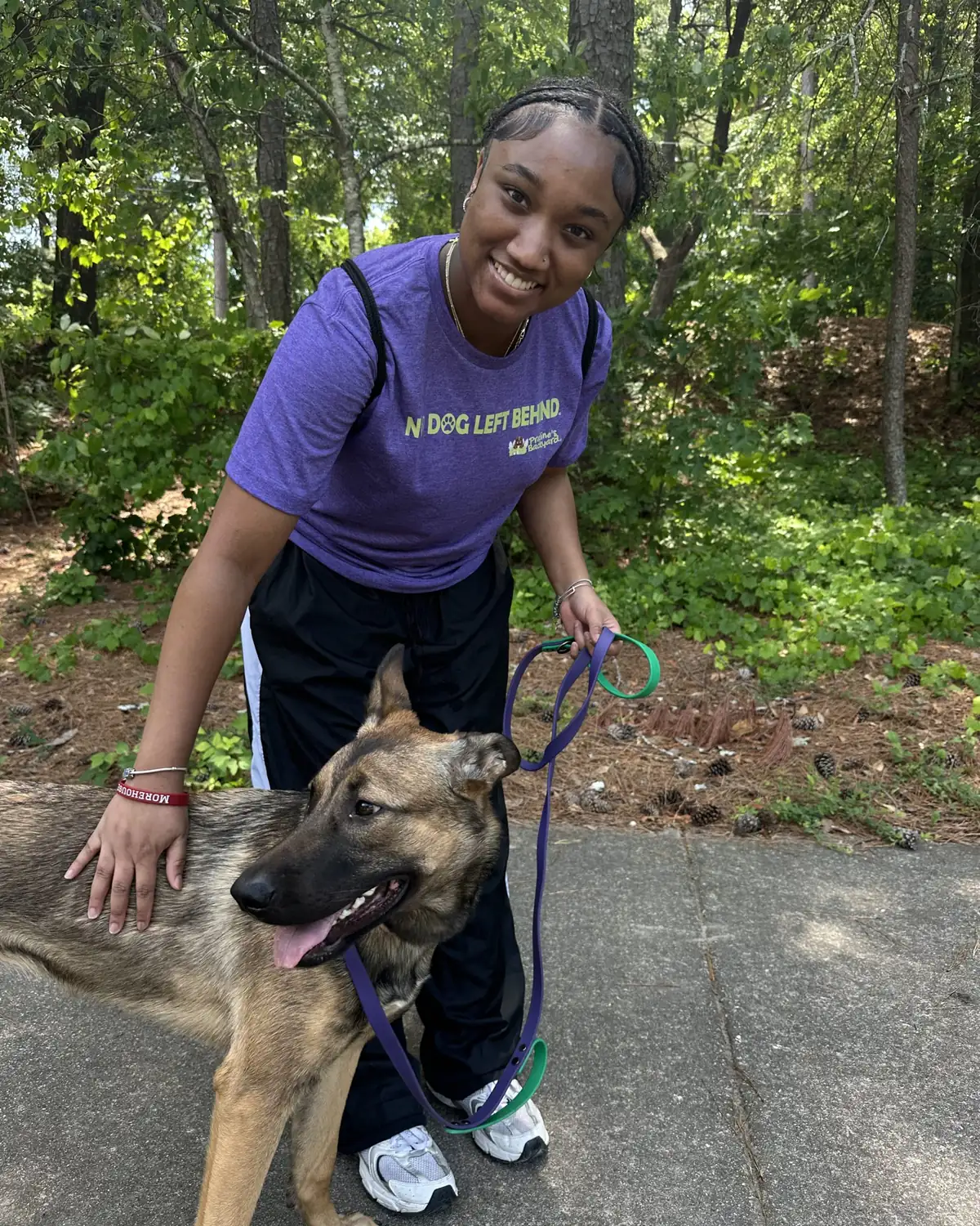 A Praline's Backyard walker on a private enrichment walk with a German Shepherd on a wooded Atlanta path